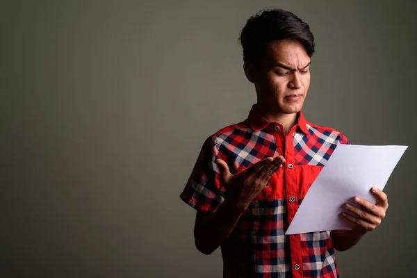 Young handsome Indian man against colored background