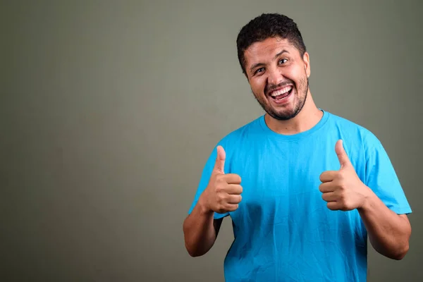 Bearded Persian man wearing blue shirt against colored backgroun — Stock Photo, Image