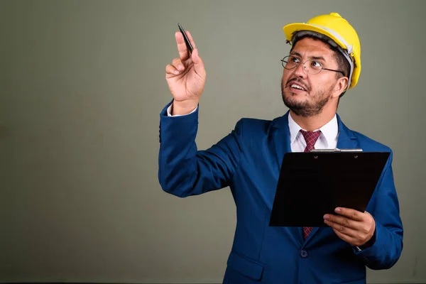 Empresario persa barbudo con sombrero de fuerza contra la espalda de color — Foto de Stock