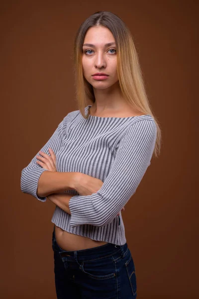 Studio colpo di giovane bella donna contro sfondo marrone — Foto Stock