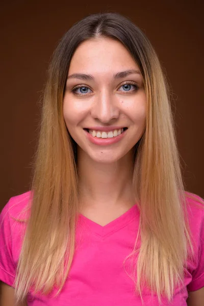 Face of young beautiful woman smiling against brown background — Stock Photo, Image