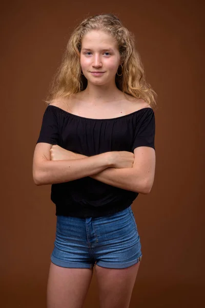 Ung vacker blond tonårstjej mot brun bakgrund — Stockfoto