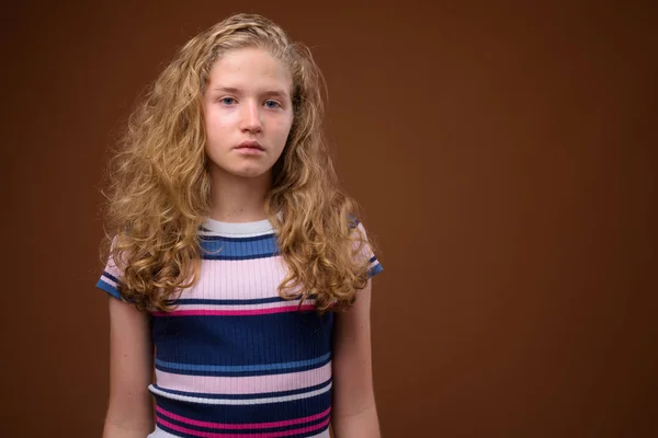 Mooie blonde tiener meisje tegen bruine achtergrond — Stockfoto
