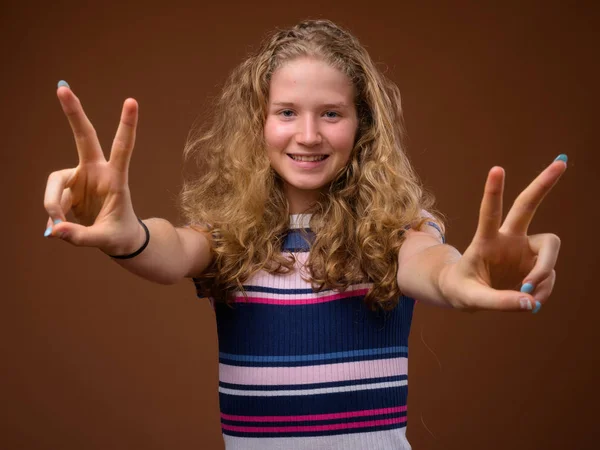 Mooie blonde tiener meisje glimlachend en vredesteken gebaar maken — Stockfoto