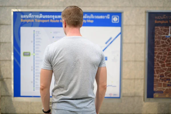 Реальный вид молодого туриста, проверяющего карту на вокзале в Бангкоке — стоковое фото