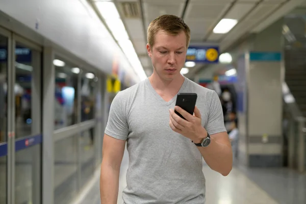 Young tourist man using phone at the underground train station in Bangkok — Stock Photo, Image