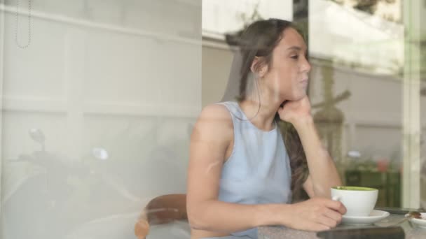 Pensativa mujer de negocios beber café y usar el teléfono mientras mira a través de la ventana — Vídeo de stock