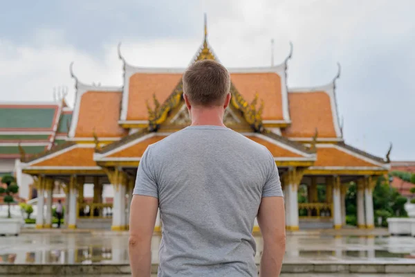 Rear view of young tourist man against view of the Buddhist temple in Bangkok — Stock Photo, Image