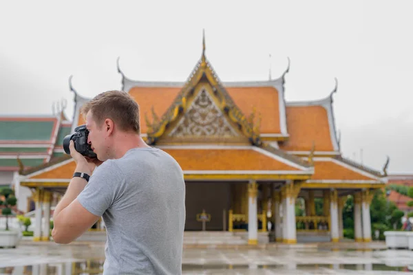 Profile view of young tourist man taking picture with camera of the Buddhist temple in Bangkok — Stock Photo, Image