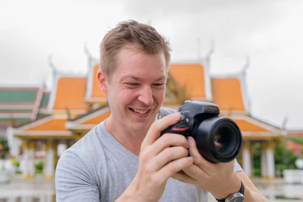 Gesicht eines glücklichen Touristenmannes, der mit der Kamera vor dem buddhistischen Tempel in Bangkok fotografiert — Stockfoto