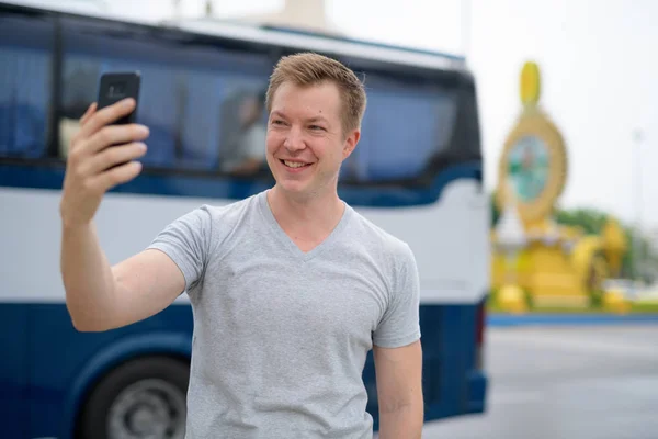 Junger glücklicher Touristenmann macht Selfie gegen Ratchadamnoen Street in Bangkok — Stockfoto