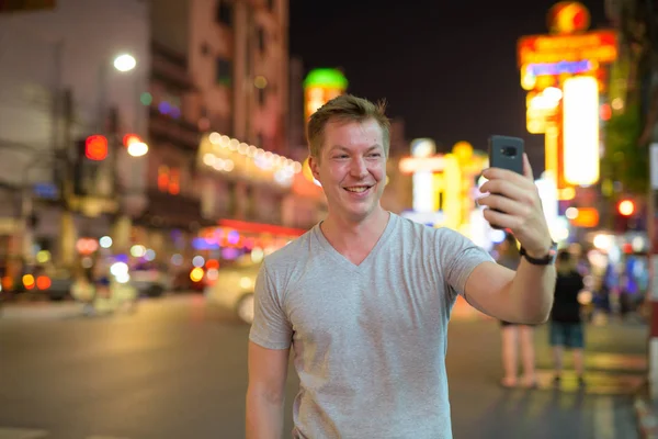 Junger glücklicher Touristenmann macht nachts Selfie in den Straßen von Chinatown — Stockfoto