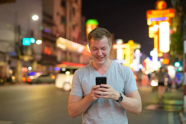 Νέοι ευτυχισμένη τουριστικά άνθρωπος χαμογελώντας ενώ χρησιμοποιώντας τηλέφωνο στους δρόμους της Chinatown, το βράδυ — Φωτογραφία Αρχείου