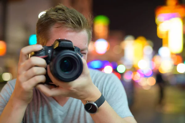 Gesicht eines jungen Touristen, der nachts mit der Kamera in den Straßen von Chinatown fotografiert — Stockfoto