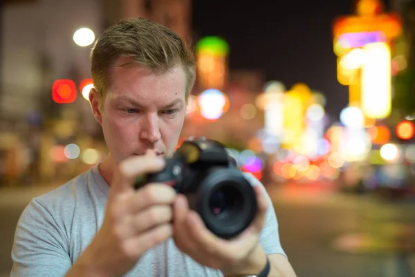Gesicht eines jungen Touristen, der nachts mit der Kamera in den Straßen von Chinatown fotografiert — Stockfoto