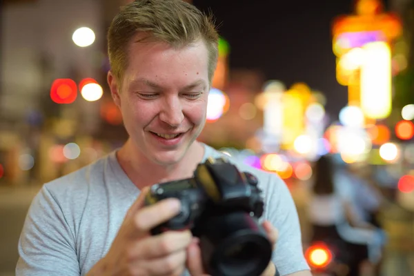 Gesicht eines jungen, glücklichen Touristen, der nachts in den Straßen von Chinatown die Kamera kontrolliert — Stockfoto