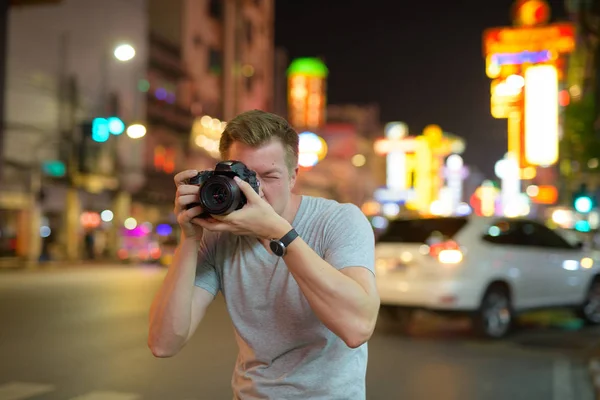 Junger Tourist fotografiert nachts mit Kamera in den Straßen von Chinatown — Stockfoto