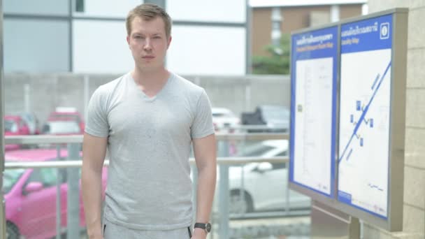 Jonge gelukkig toeristische man die lacht met armen gekruist buiten het station in Bangkok — Stockvideo