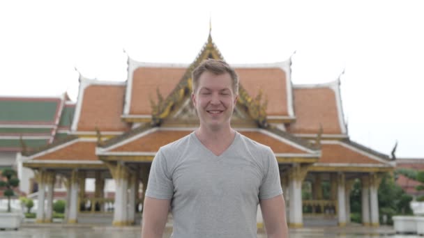 Mladí rádi turistické muž s úsměvem proti pohledu buddhistický chrám v Bangkoku — Stock video