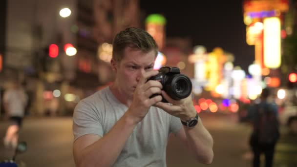 Jovem turista fotografa com câmera nas ruas de Chinatown à noite — Vídeo de Stock