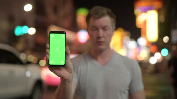 夜のバンコクのチャイナタウンの通りで若いハンサムな観光客の男のポートレート — ストック動画