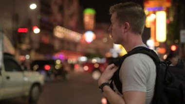 Genç Turizm adam backpacker süre istimal telefon ve taksi mahallesinde gece arama bekliyor