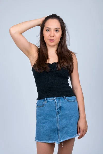 Young beautiful multi-ethnic woman brushing hair back against white background — Stock Photo, Image