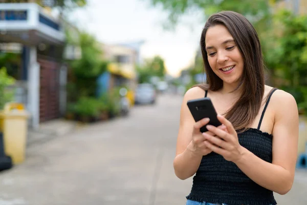Joven feliz mujer multiétnica utilizando el teléfono al aire libre — Foto de Stock