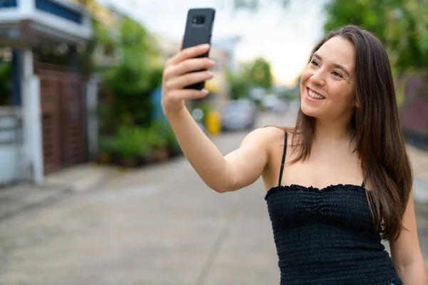 Young happy multi-ethnic woman taking selfie outdoors — Stock Photo, Image