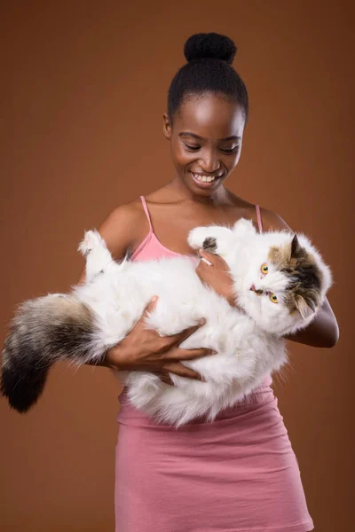 Jovem bela mulher africana Zulu segurando gato enquanto sorri — Fotografia de Stock