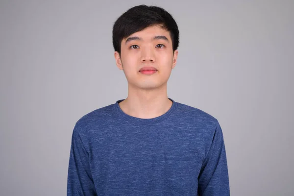 Face of young Asian man against white background