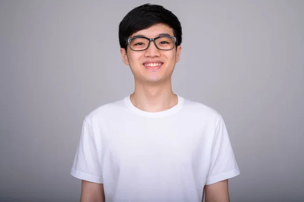 Estudio disparo de joven feliz asiático nerd hombre sonriendo mientras llevaba gafas — Foto de Stock