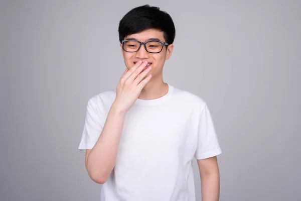 Studioaufnahme eines jungen glücklichen asiatischen Nerds, der lacht und den Mund bedeckt — Stockfoto