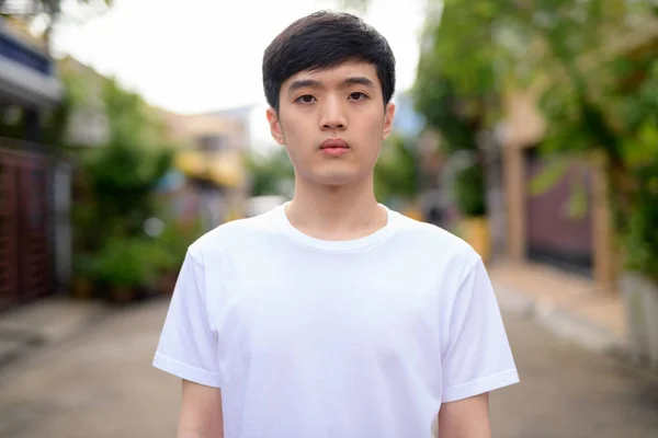 Junger asiatischer Mann schaut in die Kamera auf der Straße — Stockfoto