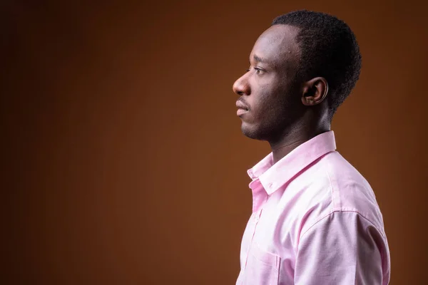 Vista de perfil de joven empresario africano sobre fondo marrón — Foto de Stock