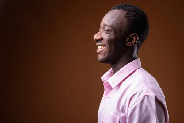 Kahverengi arka planı gülümseyen genç Afrika işadamı profil görünümü — Stok fotoğraf