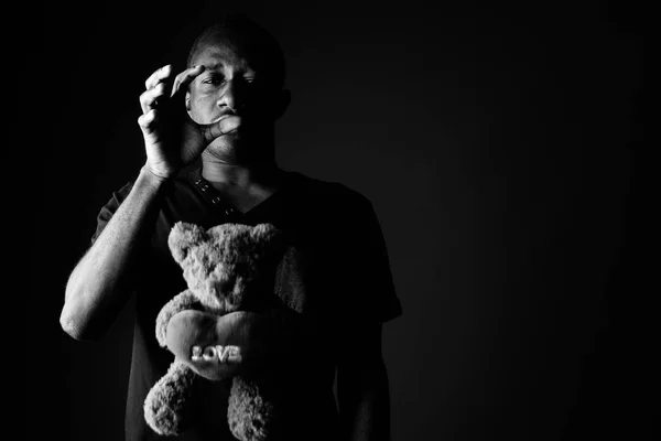 Sad depressed young African man with teddy bear and love sign text in black and white — Stock Photo, Image