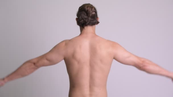 Задний вид мускулистого человека, сгибающего бицепсы без рубашки на белом фоне — стоковое видео