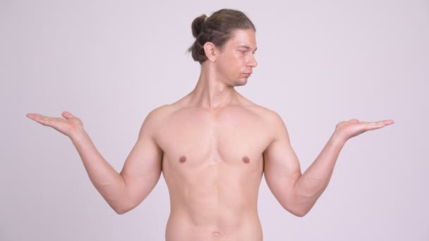 Yakışıklı kaslı gömleksiz adam bir şey karşılaştırma — Stok video