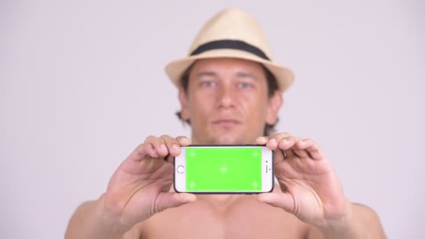 Gesicht eines glücklichen, muskulösen Touristenmannes, der sein Handy ohne Hemd zeigt — Stockvideo