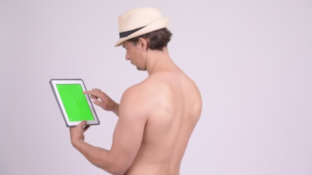 Vista trasera del hombre turista muscular utilizando tableta digital sin camisa — Vídeos de Stock