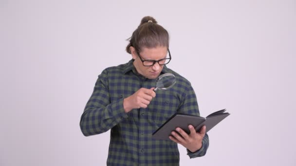 Handsome hipster man reading book with magnifying glass — Stock Video
