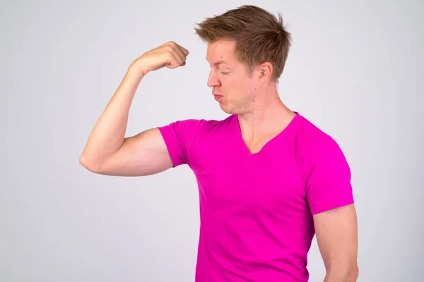 Joven hombre de aspecto divertido haciendo cara mientras flexiona los músculos — Foto de Stock