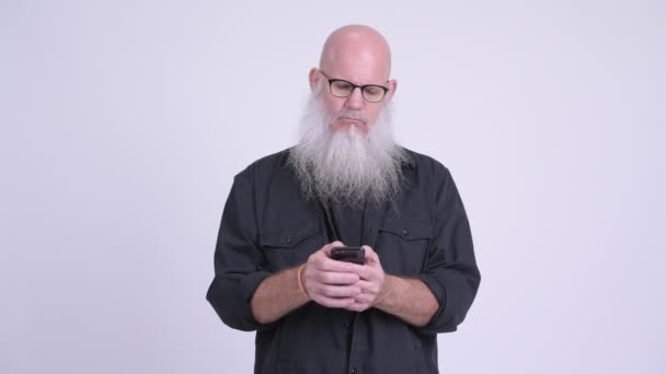 携帯電話を使用しながら笑みを浮かべて幸せな成熟したハゲひげを生やした男 — ストック動画