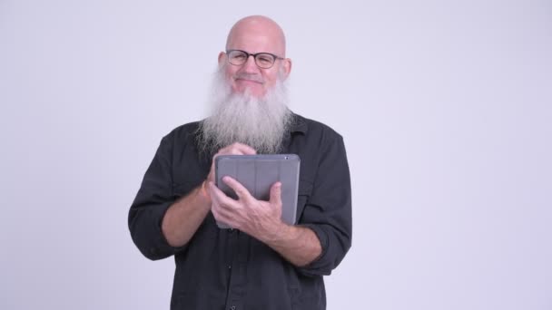 Happy mature bald bearded man thinking while using digital tablet — Stock Video