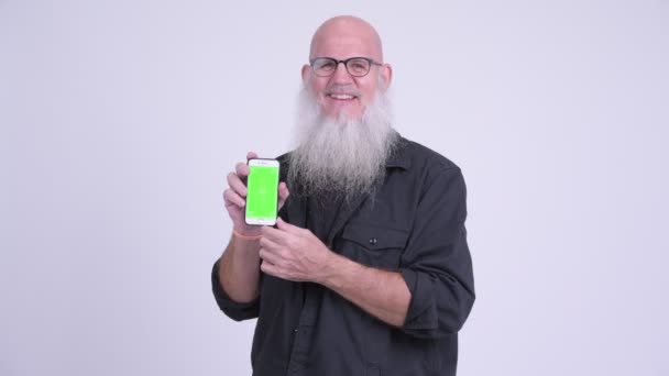 Happy mature bald bearded man showing phone — Stock Video