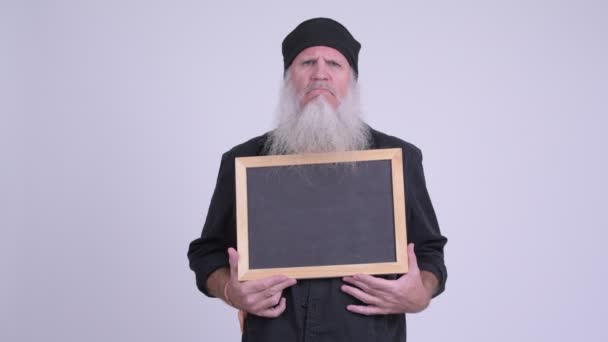 Angry mature bearded hipster man holding blackboard — Stock Video