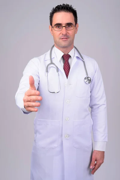 Retrato de homem bonito médico dando aperto de mão contra fundo branco — Fotografia de Stock