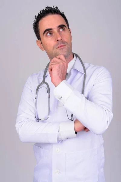 Portrait of handsome man doctor thinking against white background — Stok Foto