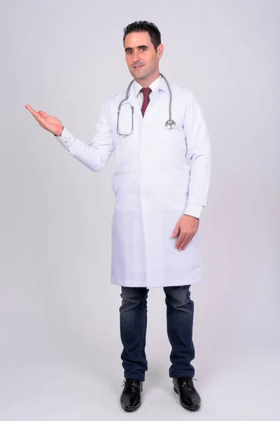 Γεμάτο σώμα πυροβολισμό του happy όμορφος άνδρας γιατρός δείχνει κάτι ενάντια σε λευκό φόντο — Φωτογραφία Αρχείου